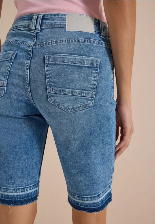 Vue de dos d’une personne portant un short en jean bleu mi-cuisses.