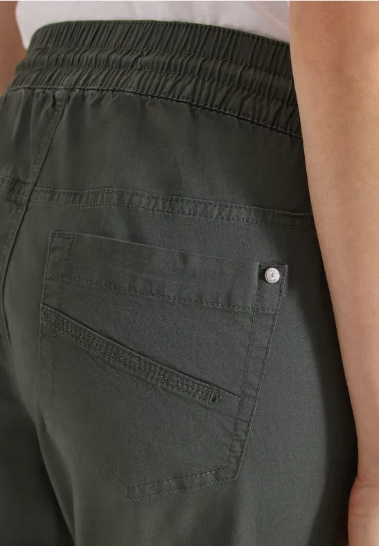 Dunkelgrüne Hose mit elastischem Bund und Gesäßstasche mit Ziernaht und Metallniete.