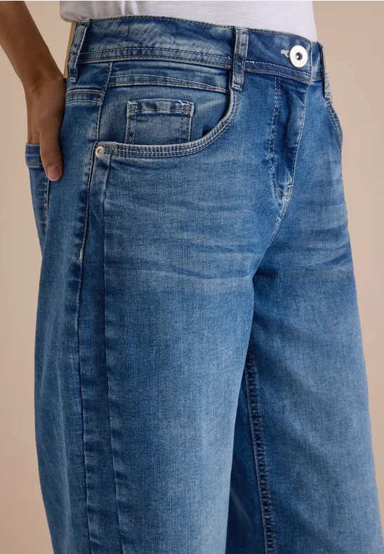 Blauer Denim-Jeans mit Hüfttaschen und dezenter Used-Optik, gezeigt von der Taille bis zu den Oberschenkeln.