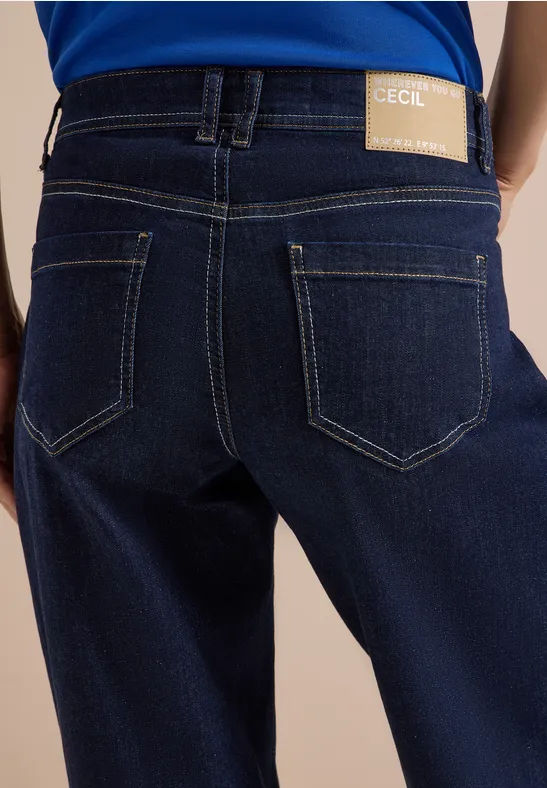 Rückansicht einer Person in dunklen Jeans mit sichtbarem Markenlabel am Bund