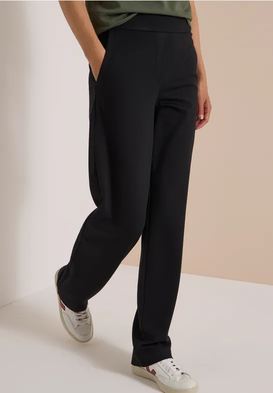 Pantalon noir à coupe droite avec poches, associé à des baskets blanches.
