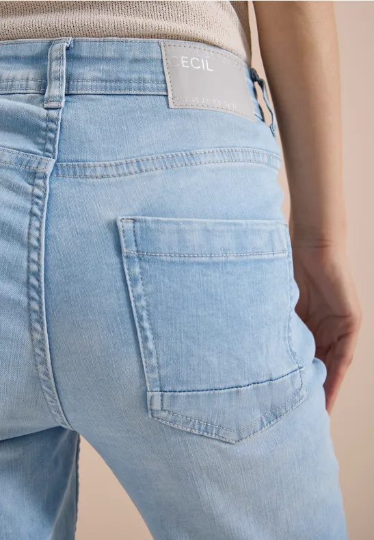 Vue arrière d'une personne portant un jean bleu clair avec poche arrière visible.