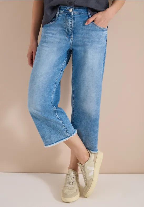 Helle, weite Jeans in Knöchellänge kombiniert mit hellen Sneaker.