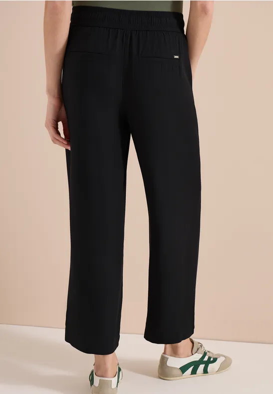 Pantalon noir ample taille haute, poches latérales et longueur mi-mollet.