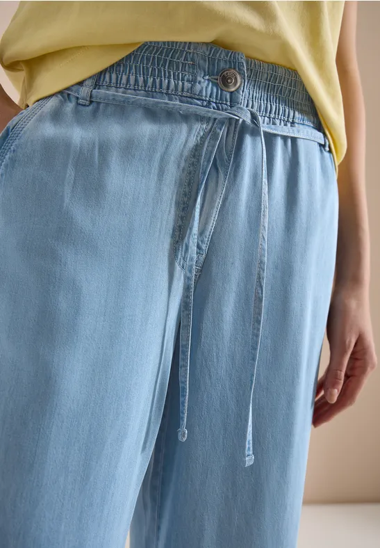 Hellblaue, locker sitzende Hose mit elastischem Bund und Kordelzug, getragen von einer Person.