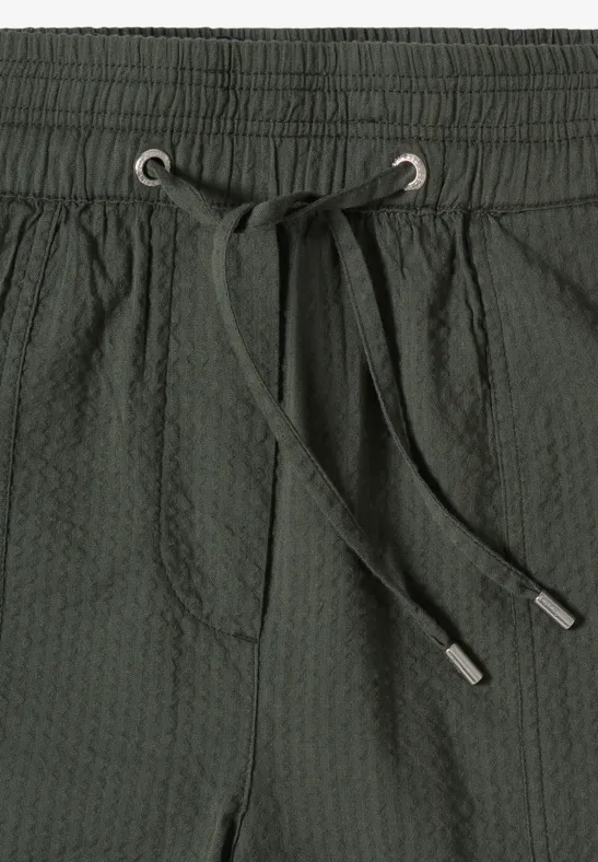 Dunkelgrüne, strukturierte Badeshorts mit elastischem Bund, Tunnelzug und vorderer Tasche.