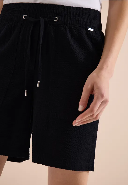 Short noir texturé avec ceinture à cordon, poche latérale et coupe décontractée.