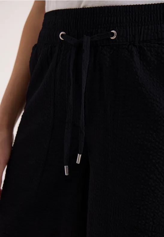 Pantalon noir texturé avec taille élastique à cordon et poches latérales.