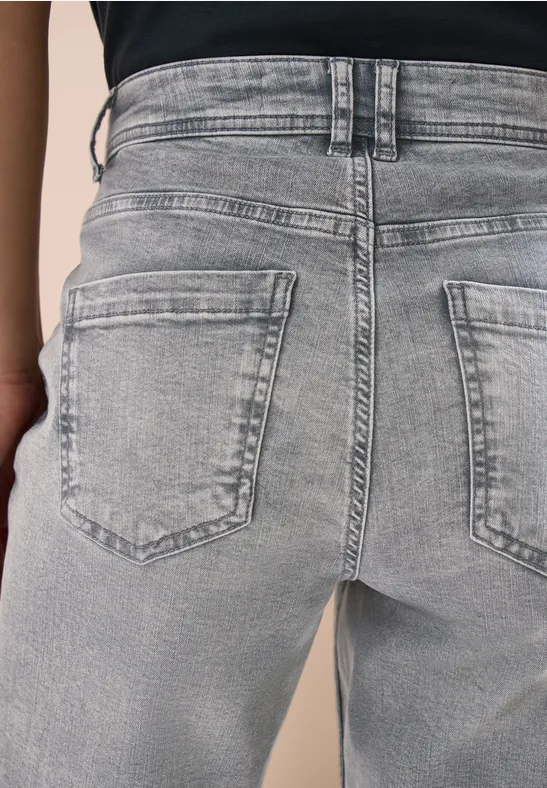 Rückansicht einer Person in hellgrauen Jeans mit aufgesetzten Gesäßtaschen.