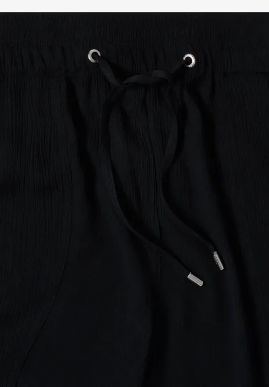 Tissu noir avec cordon de serrage et embouts métalliques argentés dans des œillets.