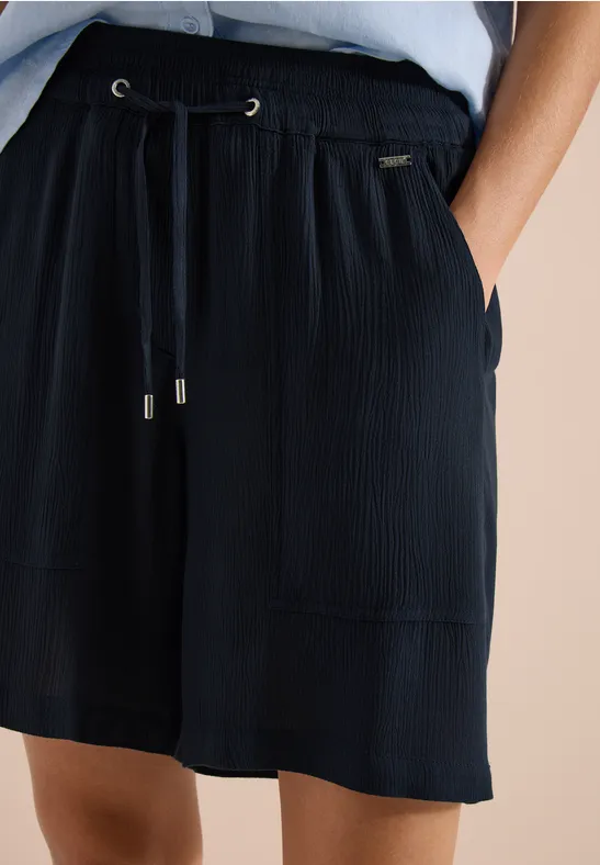 Dunkle, lockere Shorts aus Plissee-Stoff mit elastischem Bund, Kordelzug und aufgesetzten Taschen.