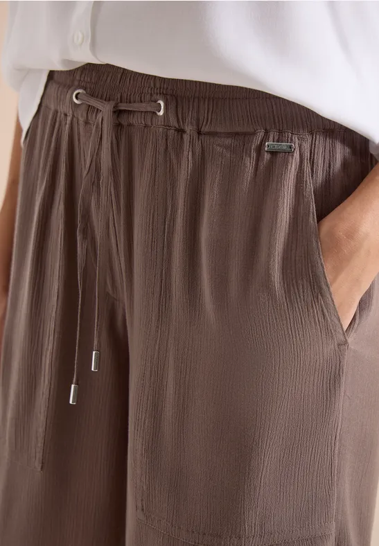 Gerippte, braune Freizeithose mit Tunnelzug und Taschen in Kombination mit weißem Oberteil