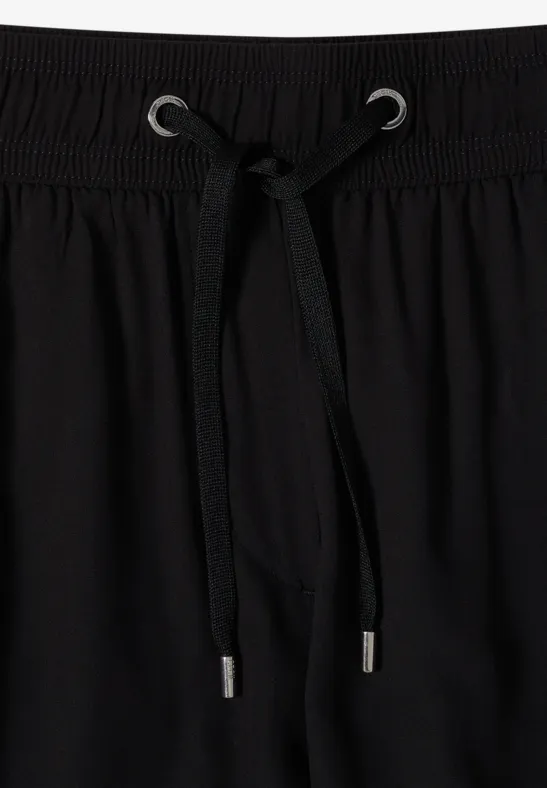 Ceinture élastique noire en tissu avec cordon de serrage.
