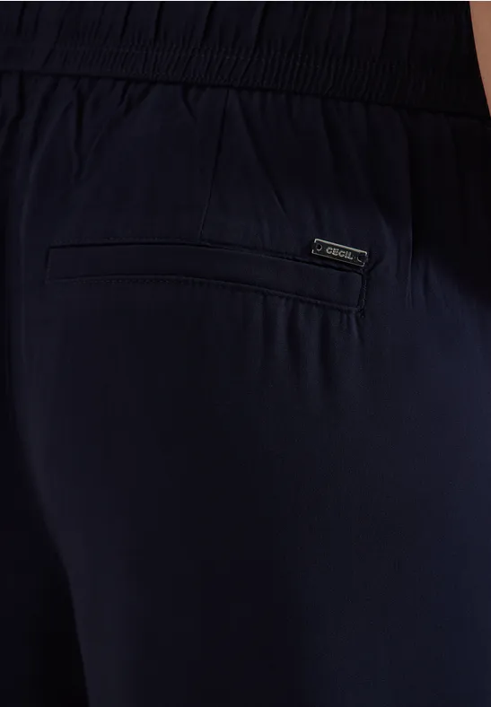Nahaufnahme einer dunkelblauen Hose mit elastischem Bund und einer Gesäßtasche mit kleinem Label