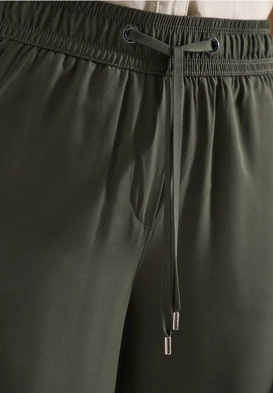Nahaufnahme einer dunkelgrünen Hose mit elastischem Bund und Kordelzug.