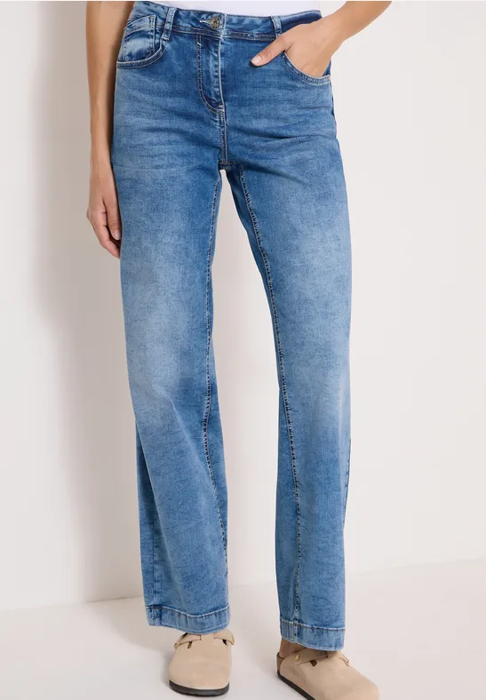 Blau gefärbte Damen-Jeans mit hohem Bund und geradem Bein, kombiniert mit hellen Sneakern.