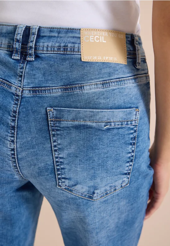 Hinteransicht einer Person in hellblauen Jeans mit Markenaufnäher 'Cecil' am Bund.