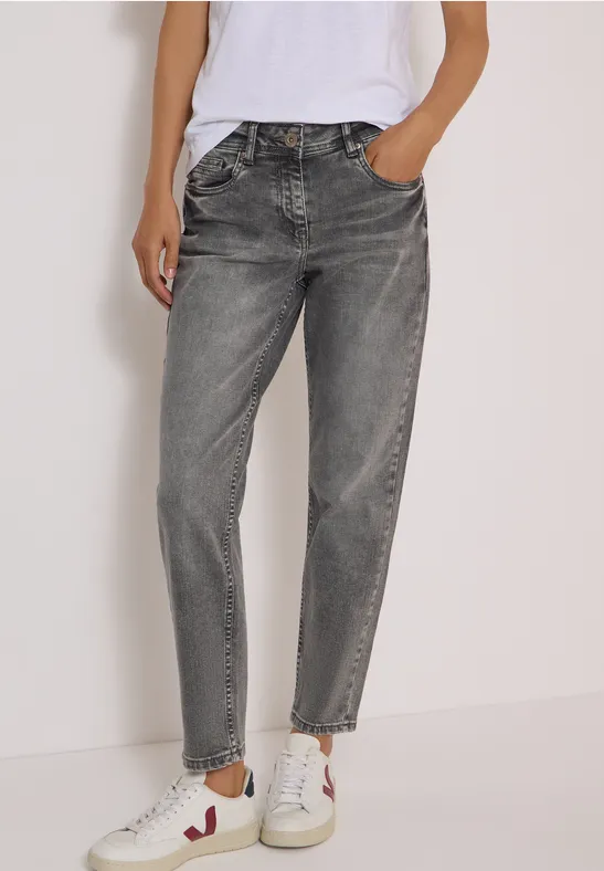 Frau trägt graue Jeans und weiße Sneaker, lässiges Outfit.