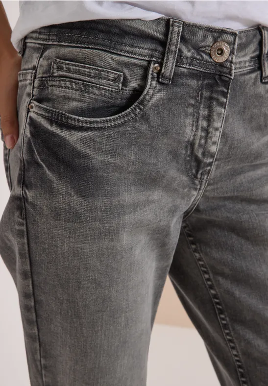 Eine Nahaufnahme von grauen, ausgewaschenen Jeans mit sichtbarer Knopfleiste und Seitentasche.
