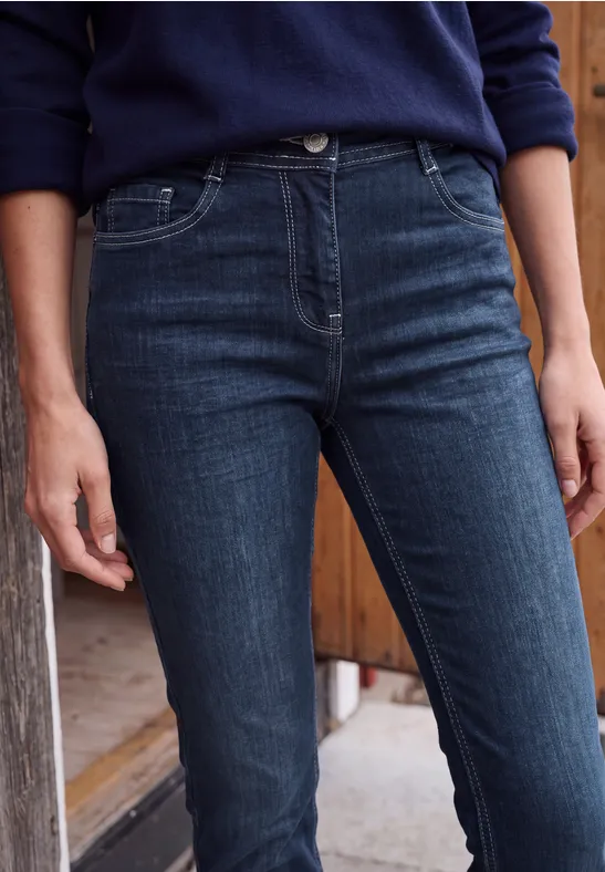Photo d'une personne en jean bleu foncé et pull bleu, vue de la taille aux cuisses.