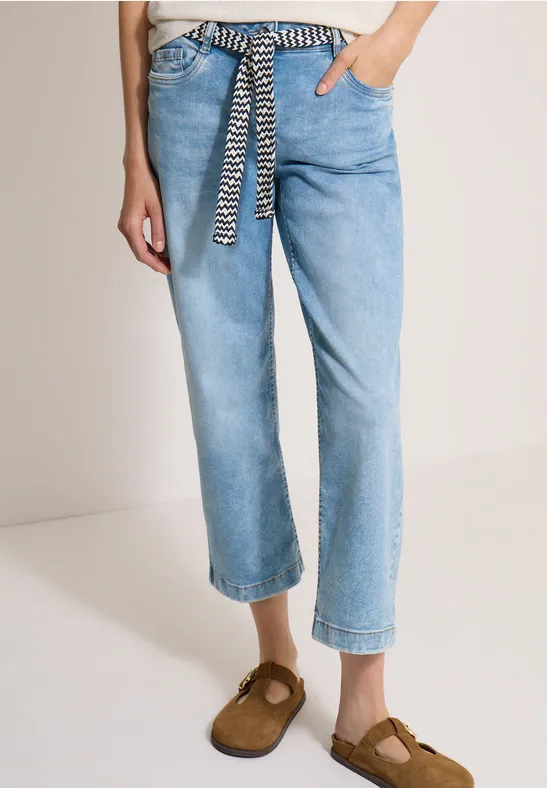 Lässige hellblaue Jeans mit Zebra-Muster-Gürtel und braunen Mokassin-Slippern, knöchellang.