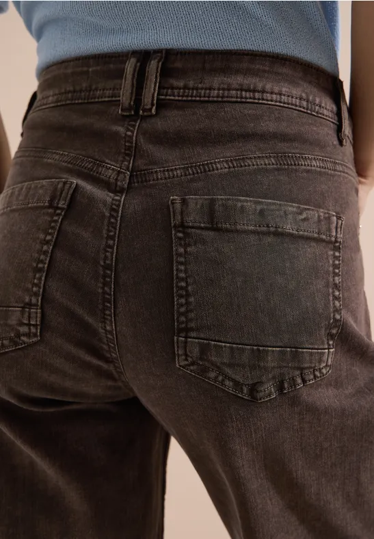 Vue arrière d'une personne portant un jean gris foncé avec poches arrière.