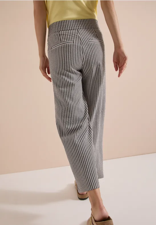 Personne vue de dos portant un pantalon ample à rayures verticales et un top jaune, style décontracté.