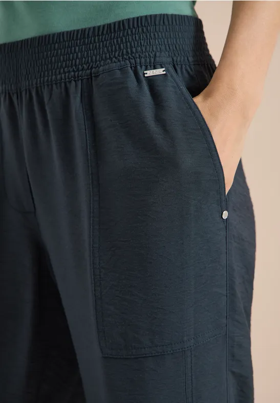 Schwarze, leicht strukturierte Hose mit elastischem Bund und seitlichen Taschen.