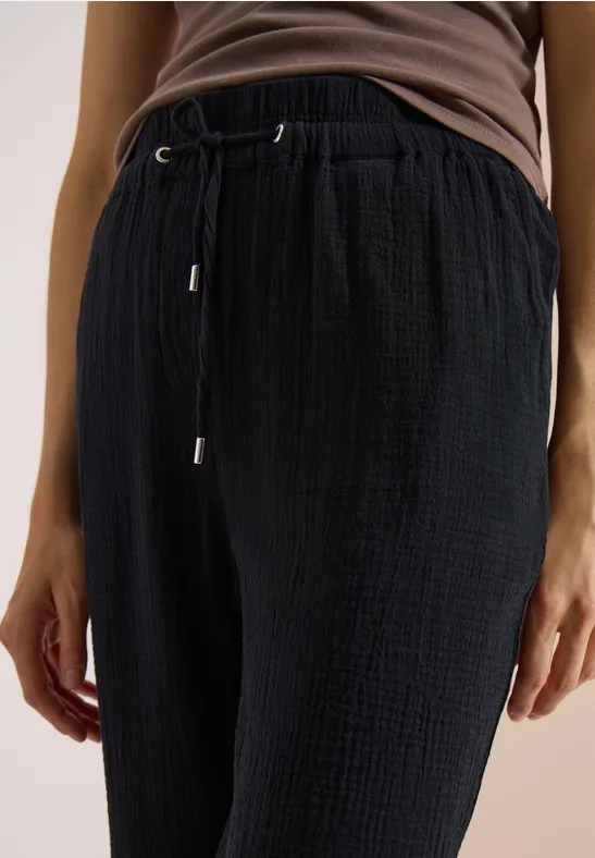 Pantalon noir texturé à cordon de serrage, porté avec un haut marron.