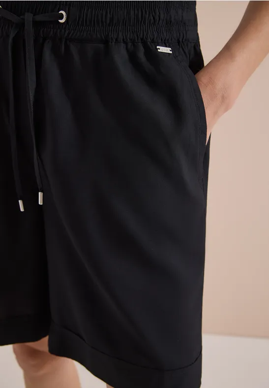 Short de sport noir mi-cuisses avec taille élastique, cordon de serrage et poches latérales.