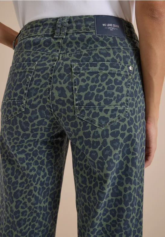 Grüne Jeanshose mit schwarzem Leopardenmuster, Rückansicht einer stehenden Person.