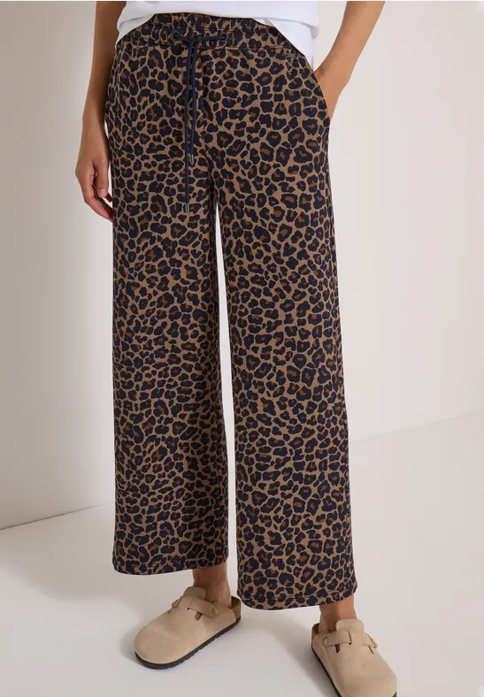 Pantalon ample à imprimé léopard, jambes larges, associé à des mocassins beiges confortables.
