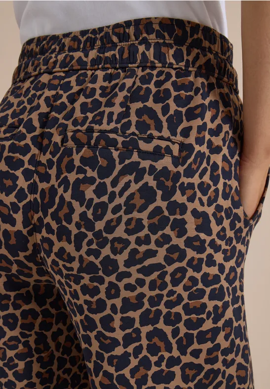 Gros plan d’un pantalon marron à imprimé léopard noir, taille élastique et poche latérale visible.