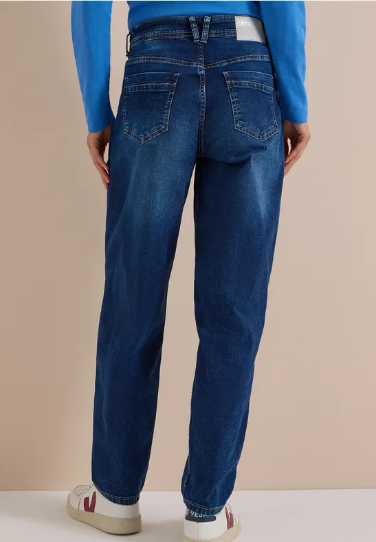 Rückenaufnahme einer Person in dunkelblauen Gerade-Jeans, weißen Sneakern und blauem Oberteil.