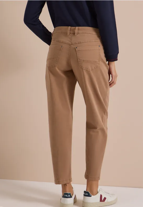 Femme vue de dos portant un pantalon chino beige à revers, un haut bleu foncé et des baskets blanches.