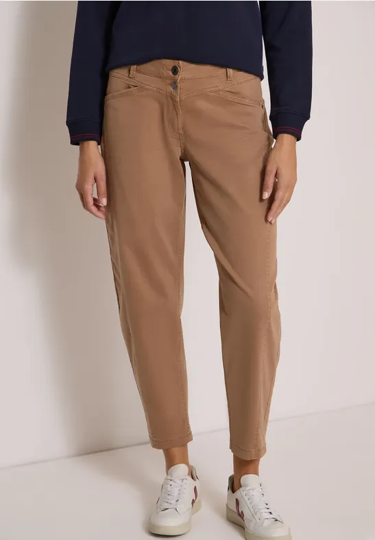 Pantalon chino marron à coupe décontractée, porté avec des baskets blanches.