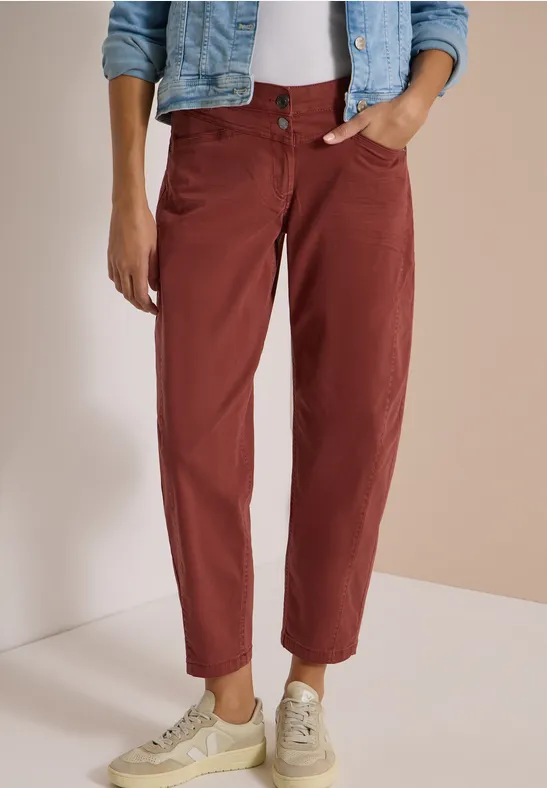Pantalon brique coupé juste au-dessus de la cheville, associé à une veste en jean, tee-shirt blanc et baskets crème