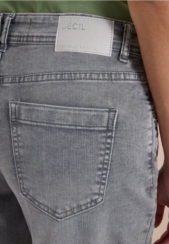 Rückansicht einer Person in grauen Jeans mit Markenlabel über der Gesäßtasche.