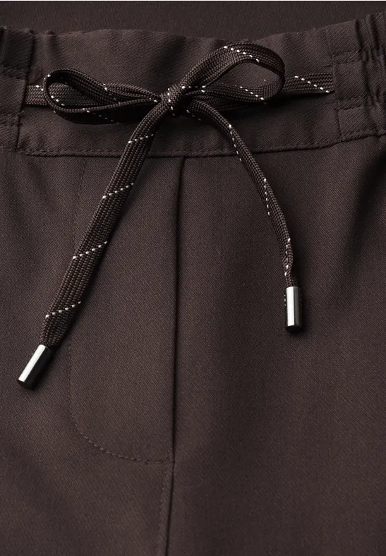 Gros plan sur un pantalon brun foncé avec cordon de serrage et poche visible.