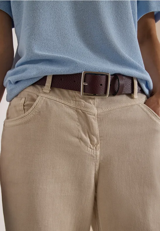 Personne porte un pantalon beige avec poches, un t-shirt bleu clair et une ceinture en cuir marron