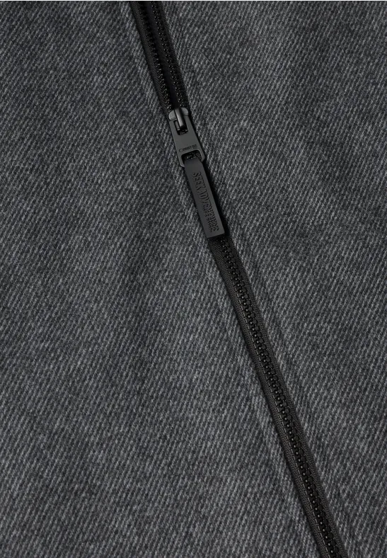 Close-up van een zwarte rits op donkergrijze stof.