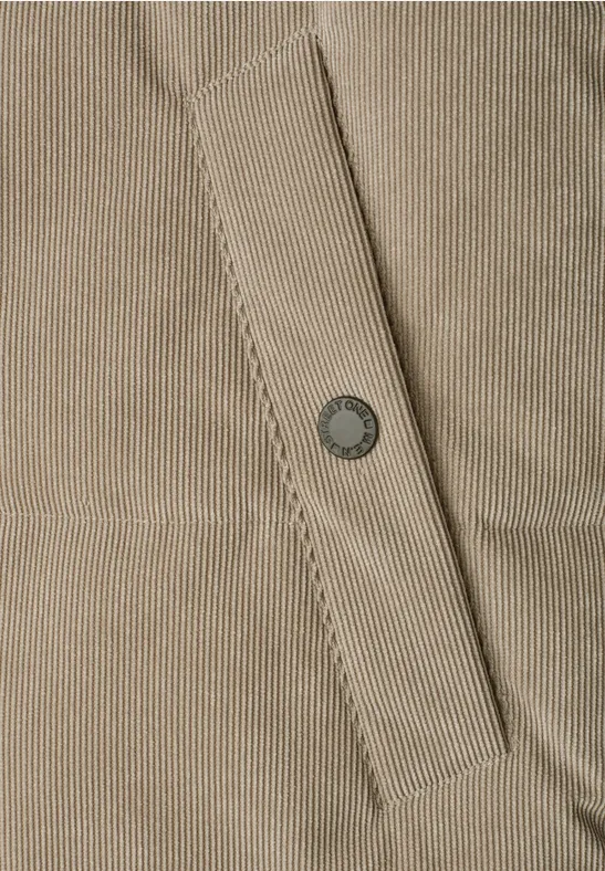 Hellbeiges Corduroy-Gewebe mit aufgesetzter Tasche und metallischem Druckknopf.