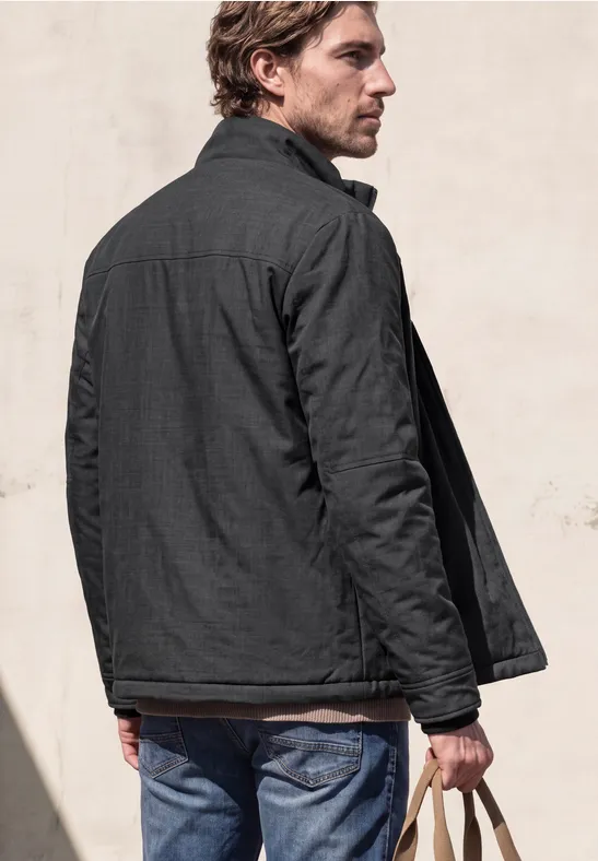 Un homme de dos porte une veste grise et un jean, tenant ses clés à la main.