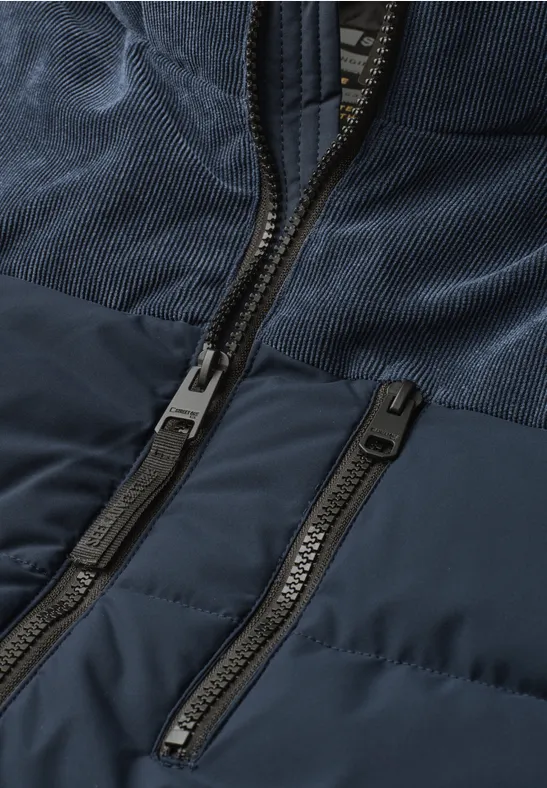 Detailansicht einer dunkelblauen Jacke mit zwei Reißverschlüssen und unterschiedlichen Stofftexturen.