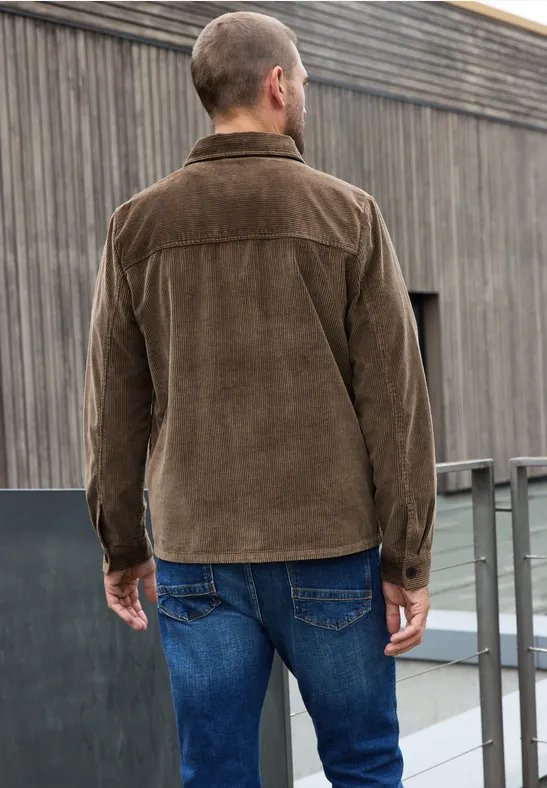 Mann steht mit dem Rücken zur Kamera und trägt eine braune Cordjacke und blaue Jeans.