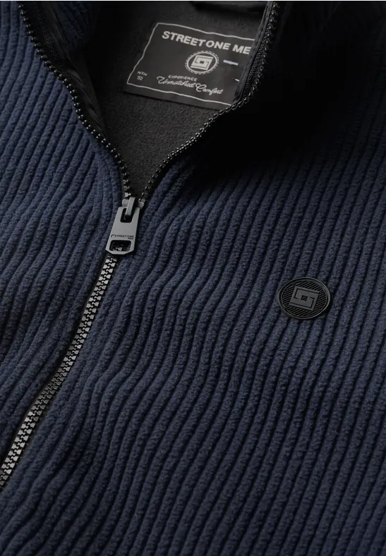 Dunkelblauer gerippter Strickcardigan mit halb geöffnetem Reißverschluss und Label am Kragen.