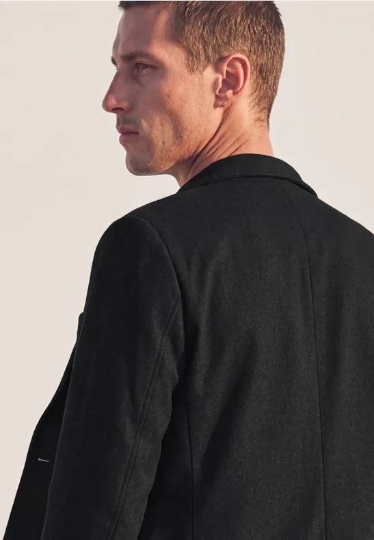 Seitliches Profil eines Mannes mit kurzem Haar in schwarzer Jacke, Blick in Richtung rechts.