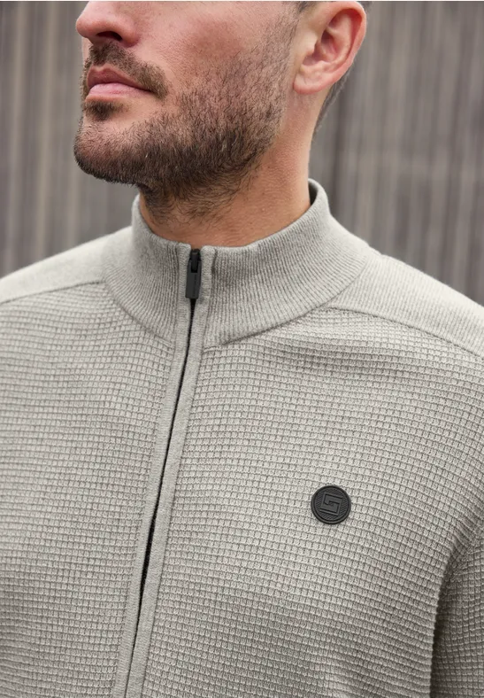 Nahaufnahme eines Mannes im grauen Strick-Zip-Up-Pullover mit rundem Logo