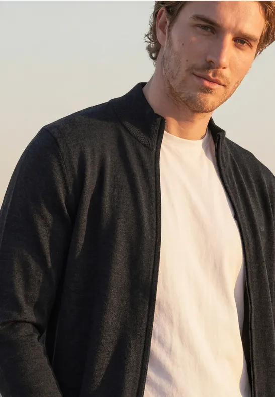 Ein Mann in weißem T-Shirt und schwarzer Jacke blickt in die Kamera.
