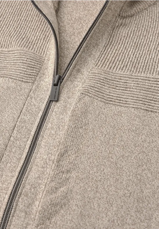 Beige Strickjacke mit Reißverschluss und feinen Rippdetails im oberen Brustbereich.